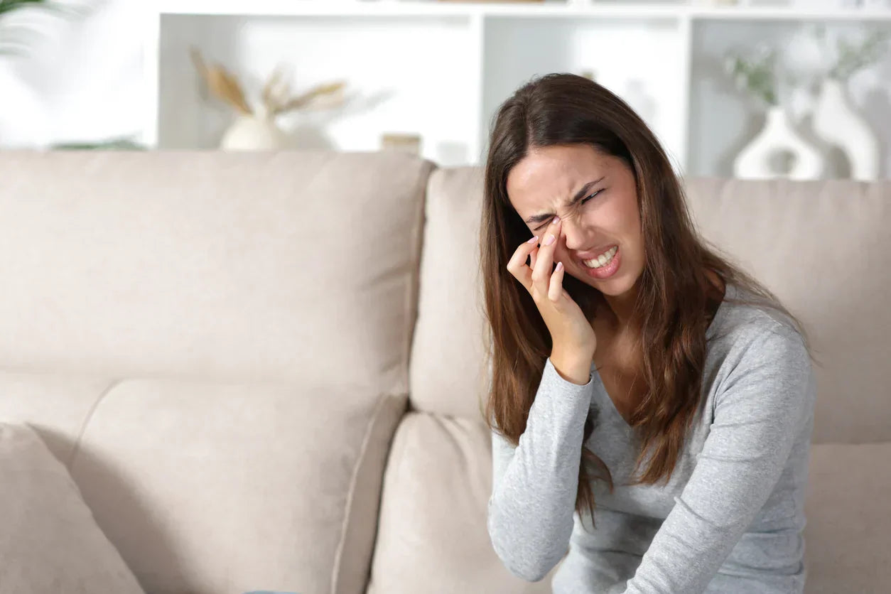 Woman on the sofa scratching her painful eye